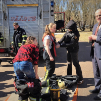 Õpilased proovivad selga päästjate varustust, nõunik Priit Männik ja paar päästjat vaatavad muheledes kõrvalt.